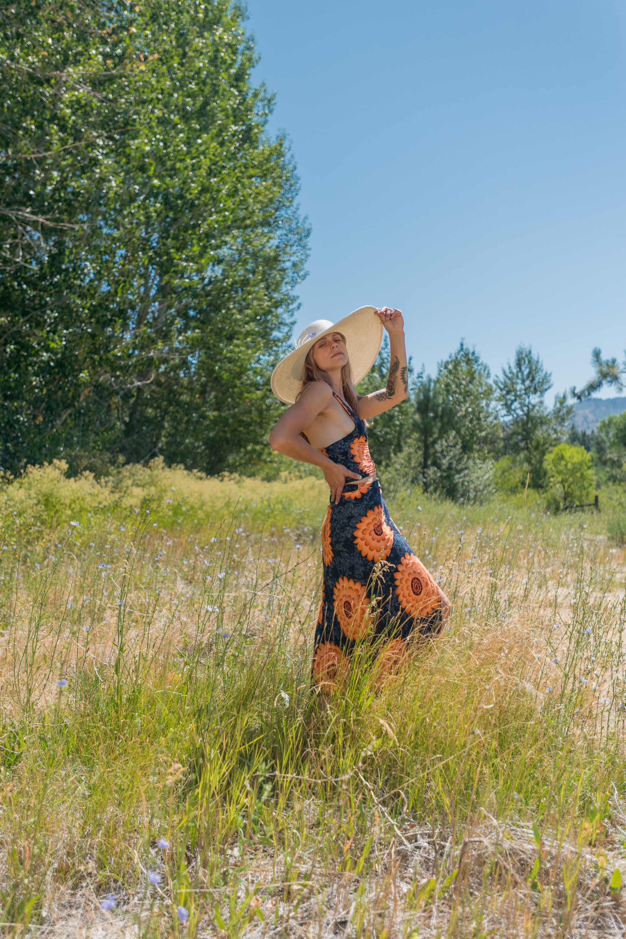 A woman standing in a sunflower dress in a Reno portrait in a grass field.